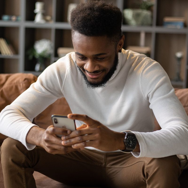 Une personne chez elle regarde son téléphone en souriant