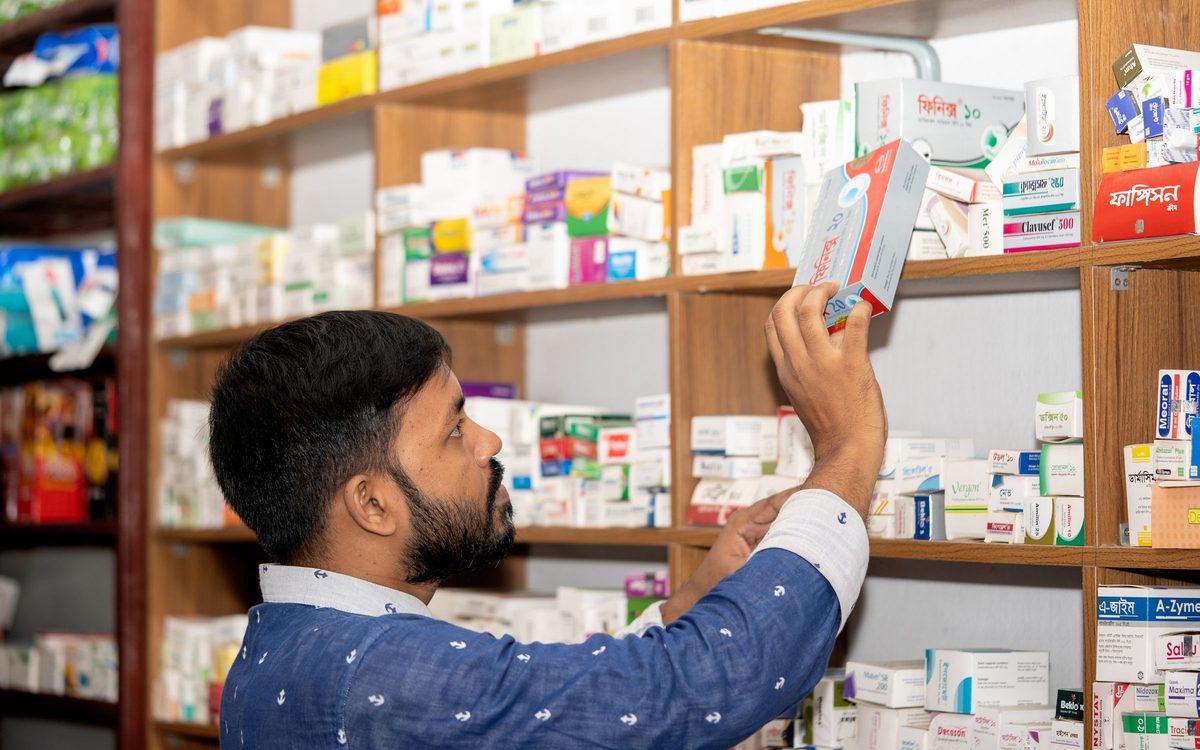 Un pharmacien prend une boîte dans le rayon de son officine