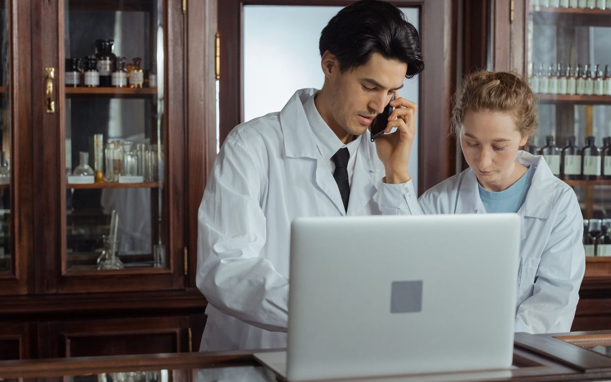 Deux pharmaciens devant l’ordinateur du comptoir, l’un au téléphone