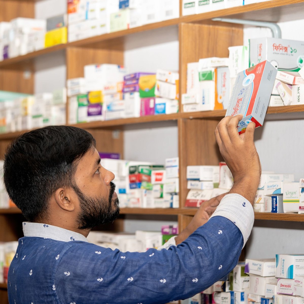 Un pharmacien prend un produit dans le rayon de son officine