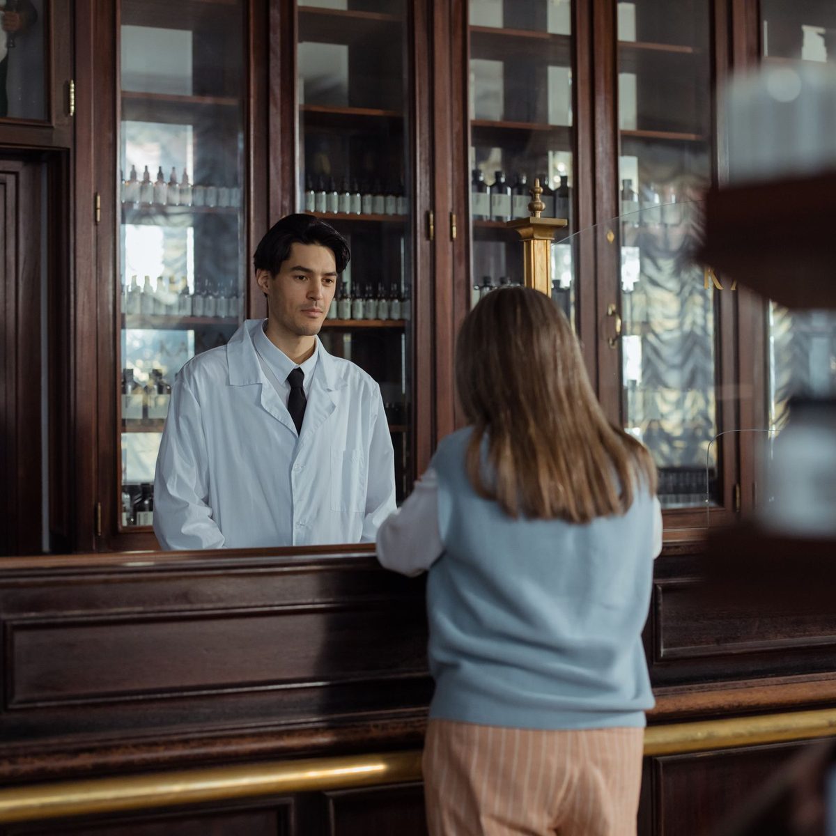 Un pharmacien au comptoir de son officine, face à une cliente