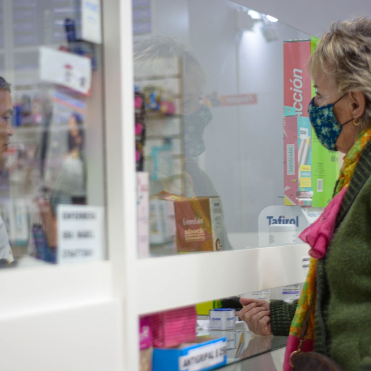 Un pharmacien sert une cliente au comptoir de son officine