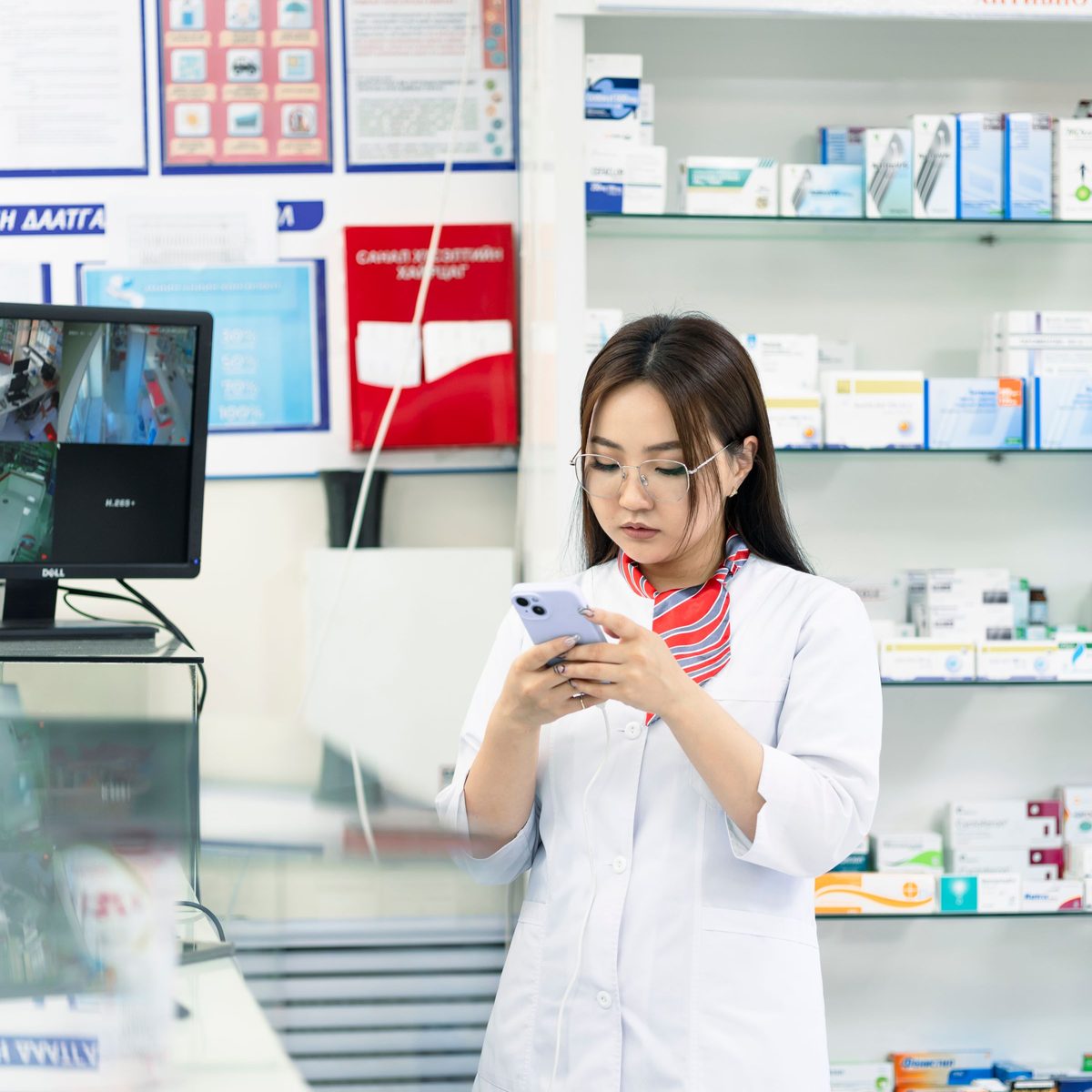 Une pharmacienne consulte son téléphone au comptoir de son officine