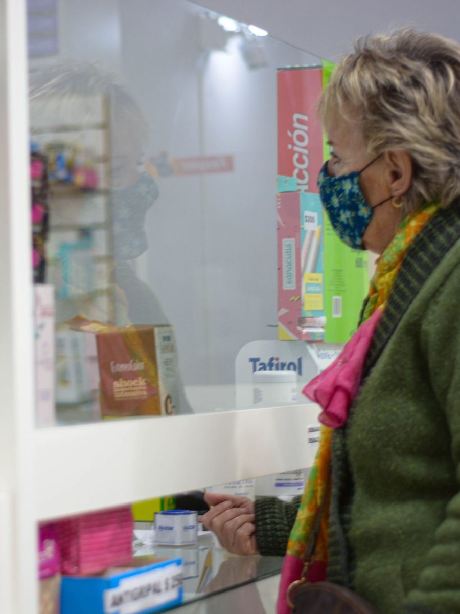 Une cliente parle au comptoir d’une officine