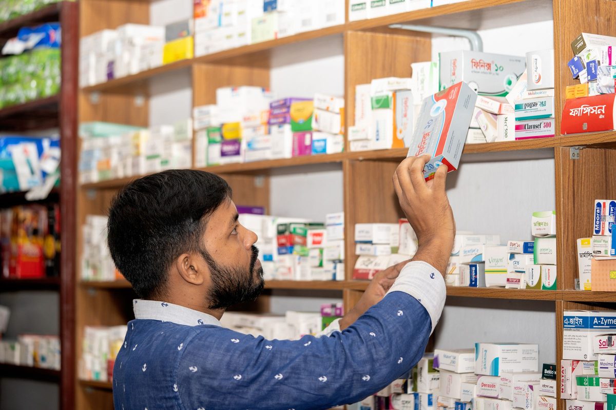 Un pharmacien prend une boîte sur l’étagère de son officine
