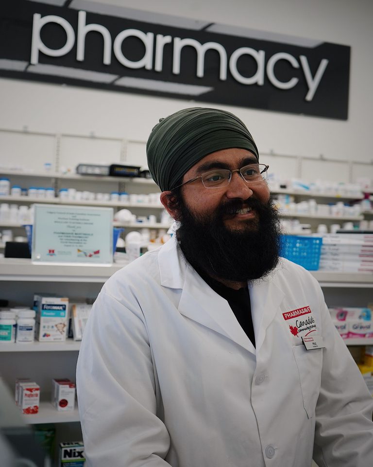 Un pharmacien souriant devant les rayons de son officine
