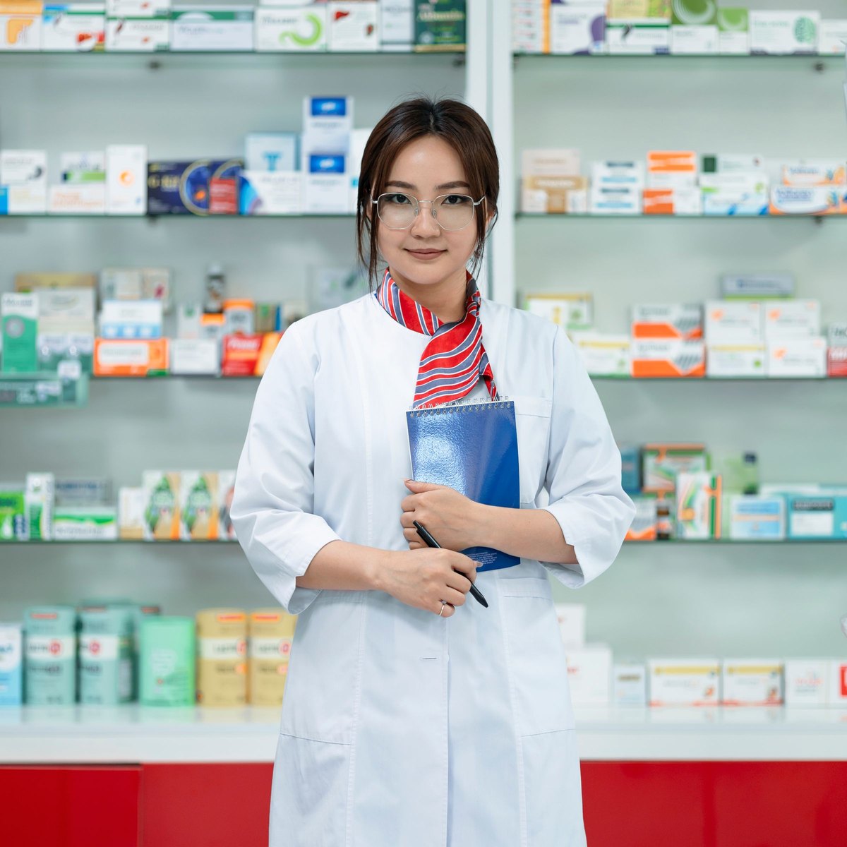 Une pharmacienne souriante, devant les rayons de son officine