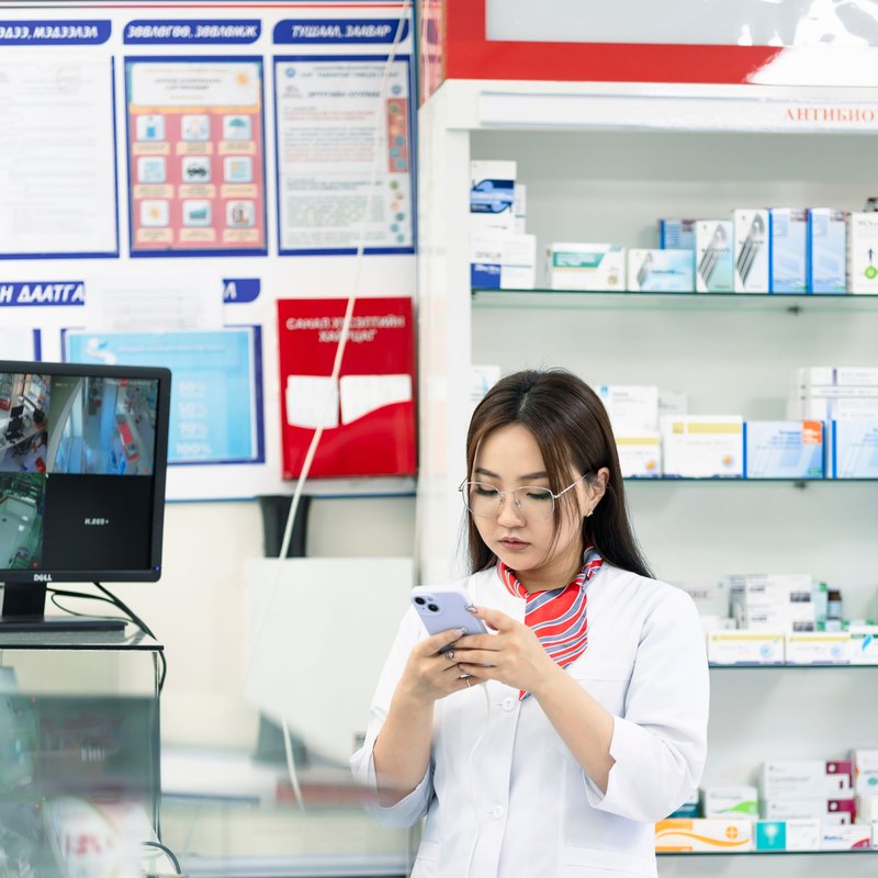 Une pharmacienne consulte son téléphone au comptoir